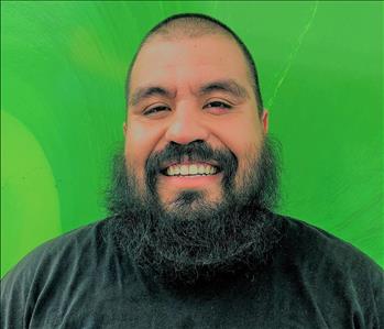 Male employee smiling in front of a green background 
