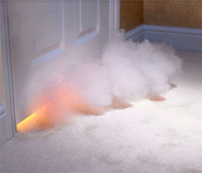 smoke coming from under the crack of the door of a room with a fire in it