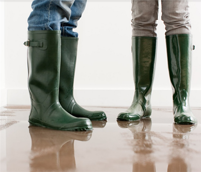 a flooded room with two people in rain boots standing in it