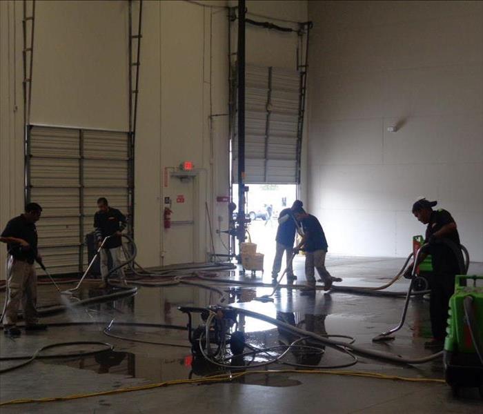 People cleaning up water in a warehouse.